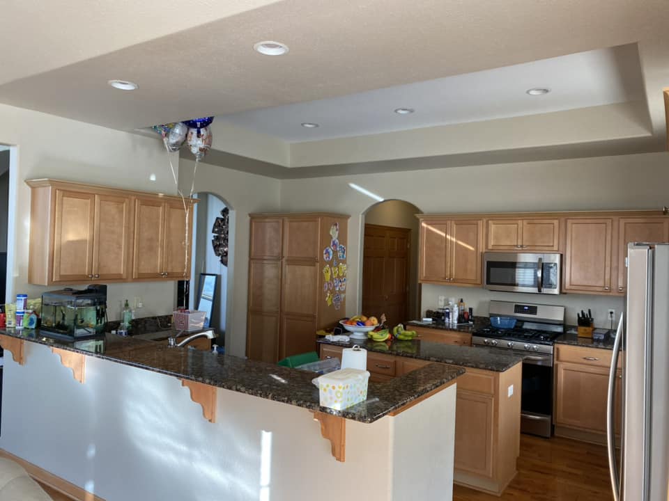 Existing kitchen before renovation with honey-oak cabinet peninsula, dark granite countertops, and stainless appliances